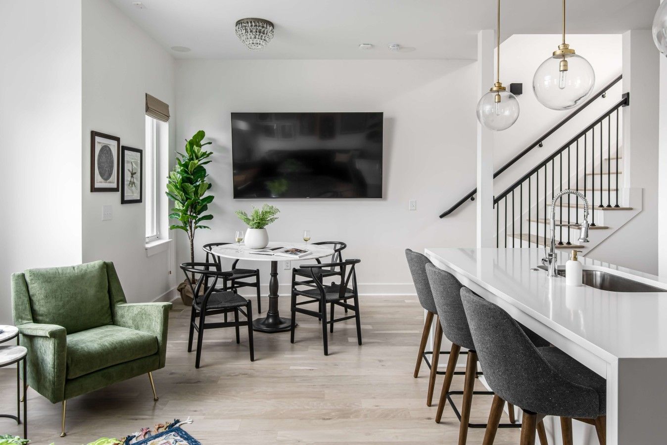 A modern kitchen with a white countertop, black chairs, and a dining table.