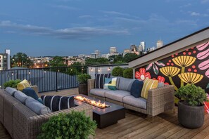 A rooftop terrace with wicker furniture, a fire feature, and a cityscape view. - Casa Paradisa • Rooftop, Fire Pit, Skyline Views (Nashville)
