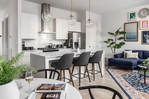 A modern kitchen with white cabinets, a central island, and bar stools.