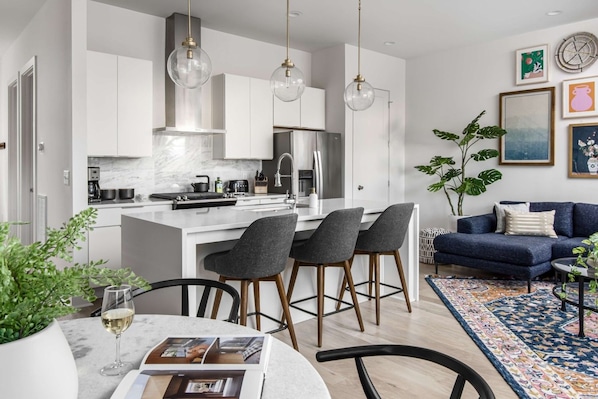 A modern kitchen with white cabinets, a central island, and bar stools.