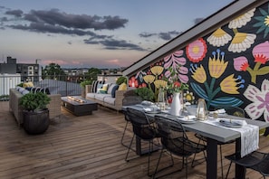 A rooftop terrace with a dining area, outdoor seating, and a colorful floral mural. - Casa Paradisa • Rooftop, Fire Pit, Skyline Views (Nashville)