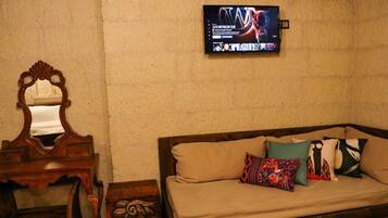 Una habitación con una cama y cómoda de madera, un espejo y un televisor instalado en la pared.