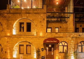 Un bâtiment en pierre doté de fenêtres en arc de cercle et d’une enseigne indiquant « Olivia Cave Hotel ».