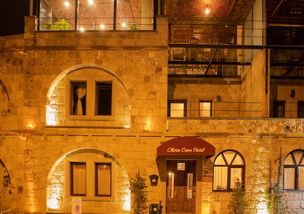A stone building with arched windows and a sign reading "Olivia Cave Hotel."