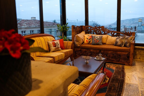 A cozy living room with a sofa, a coffee table, and a view of the city through large windows.