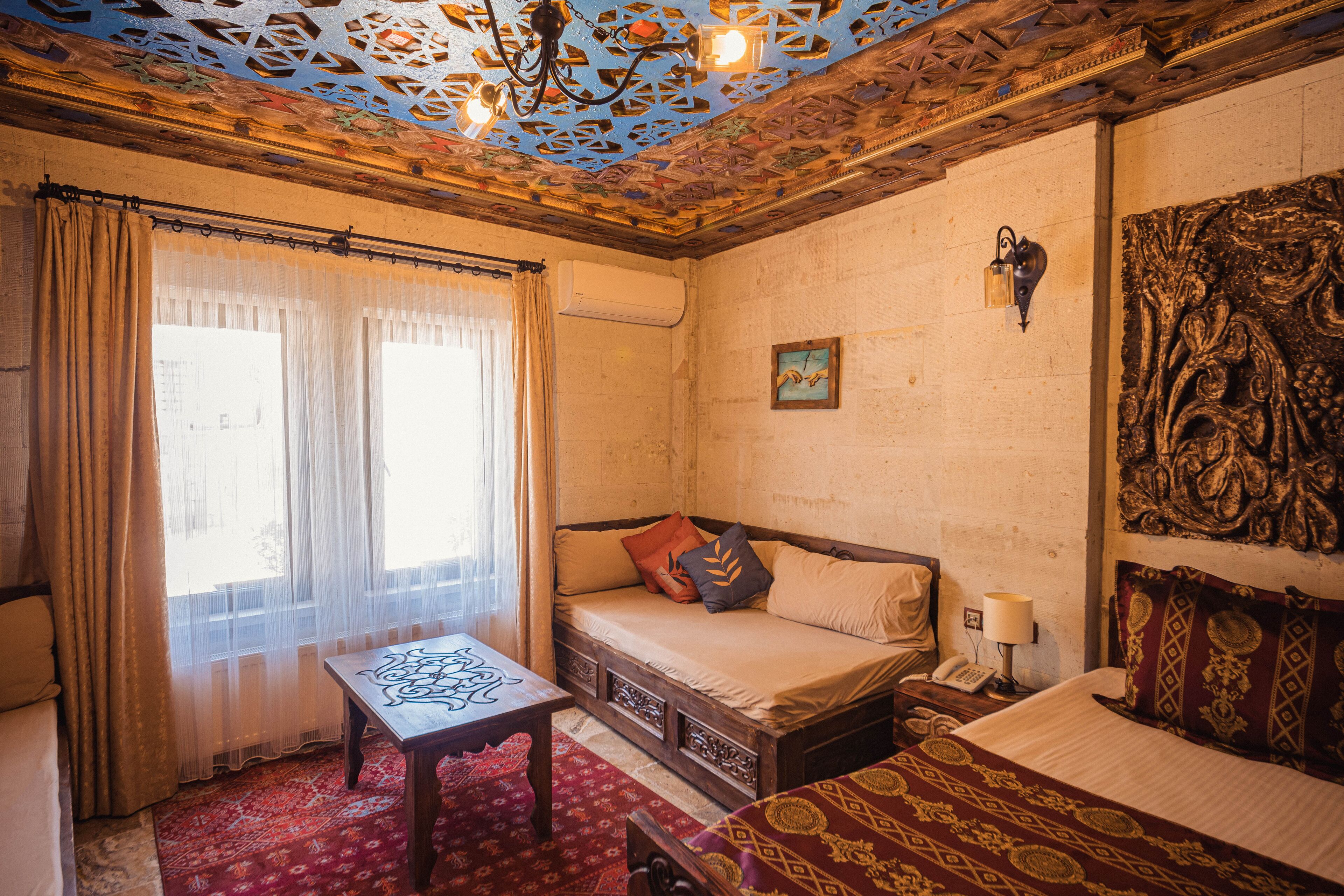 A room with a bed, a table, and a patterned ceiling.