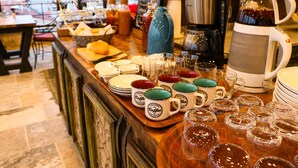 A breakfast buffet with coffee mugs, glasses, and a coffee maker. - Olivia Cave Hotel (Nevsehir)