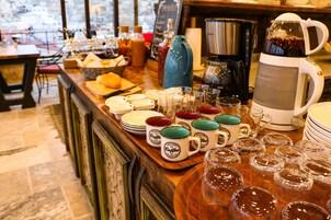 Un buffet de petit-déjeuner avec des tasses, des verres et une machine à café.