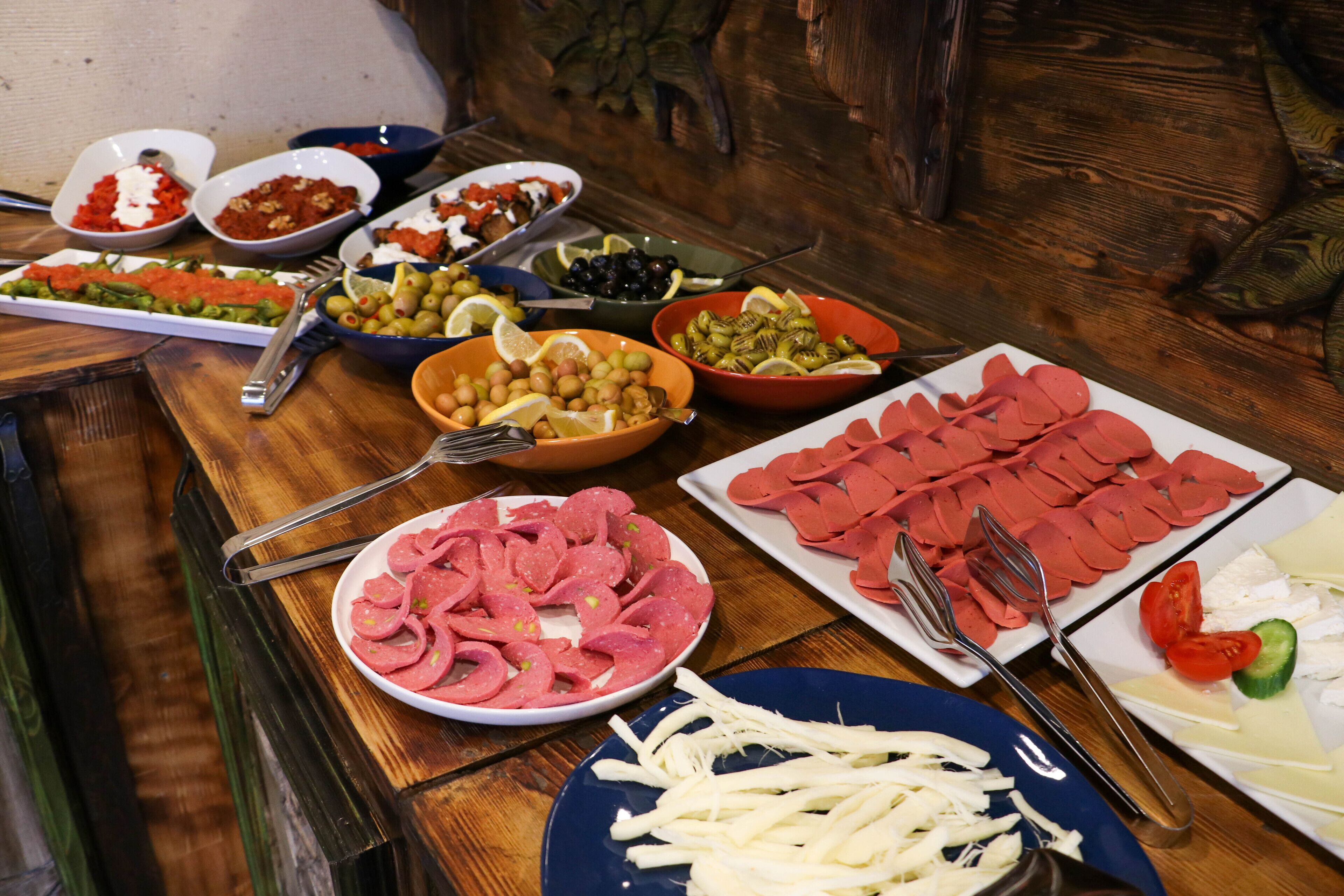 A buffet table with various food items including sliced meats, cheeses, olives, and vegetables.