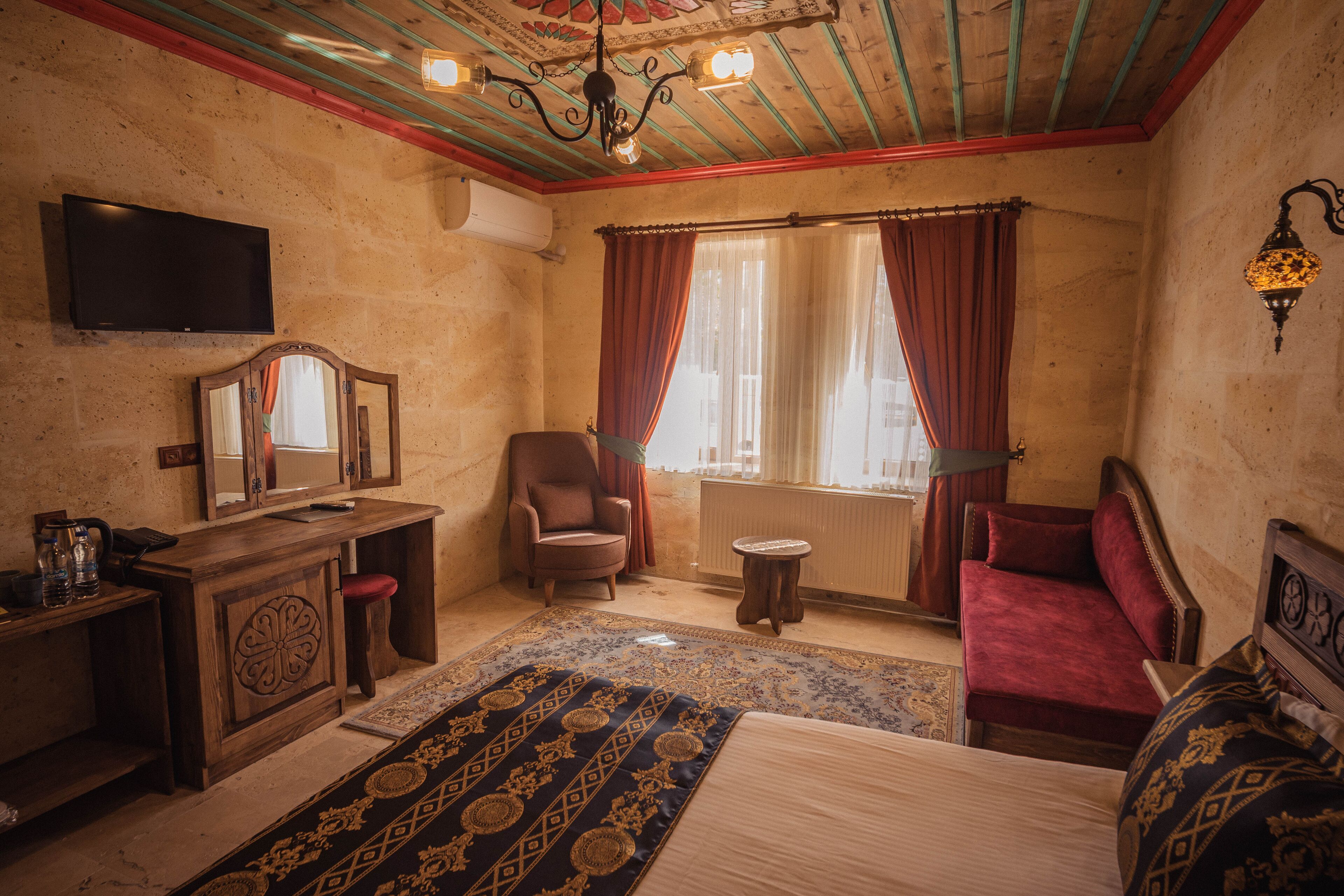 A room with a bed, a chair, a small table, a mirror, and a television.