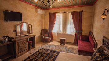 A room with a bed, a chair, a small table, a mirror, and a television.