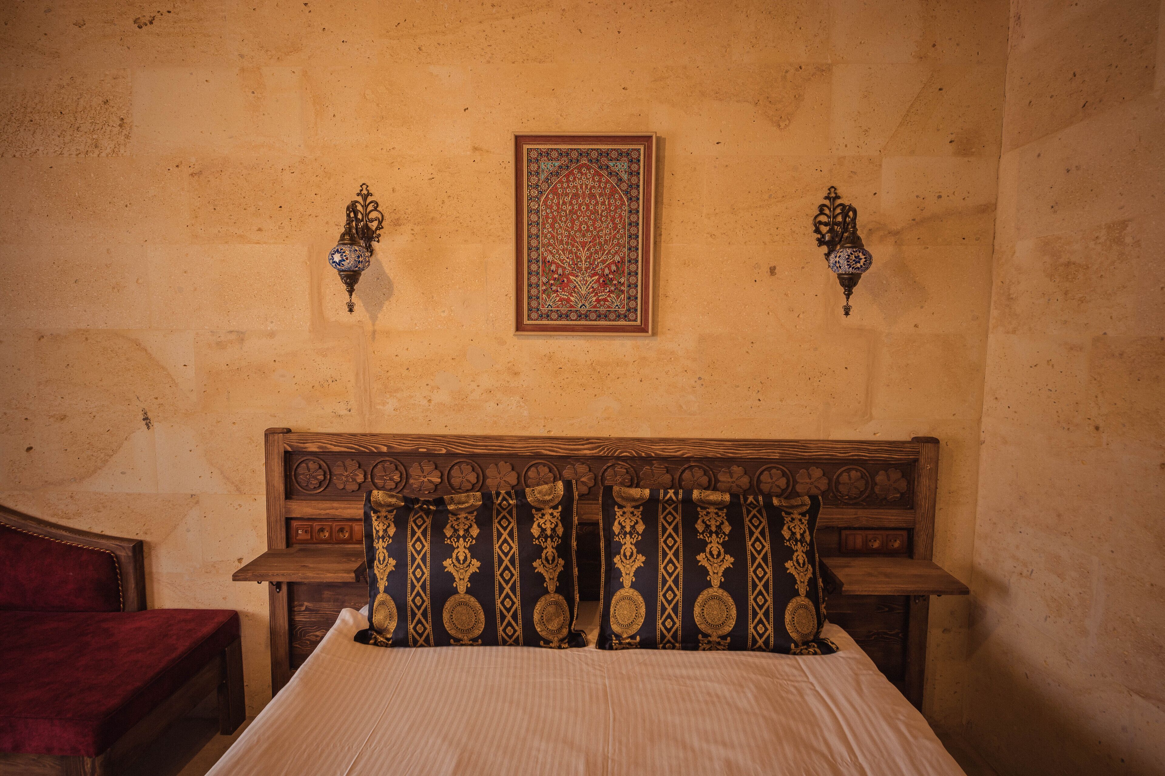 Un dormitorio con cabecera de madera, cama con ropa de cama a rayas y dos lámparas fijadas a la pared.