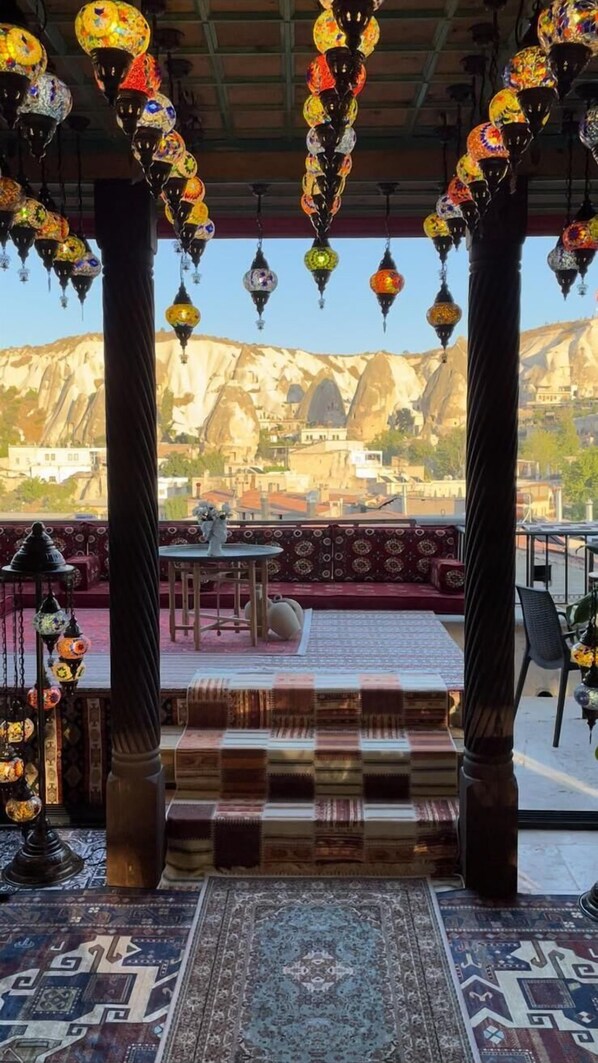 Una habitación con vistas a montañas, una alfombra estampada y faroles colgantes.