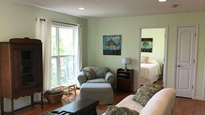 A living room with a sofa, armchair, wooden cabinet, and a painting on the wall. - Scout's Hideaway on Beautiful Smith Lake (Arley)
