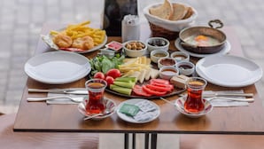 A table set with various food items, including bread, eggs, and vegetables, along with two glasses of tea. - Mai Otel Cunda (Ayvalik)