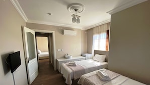 A hotel room with two beds, a TV, a desk, and a chair. - Mai Otel Cunda (Ayvalik)