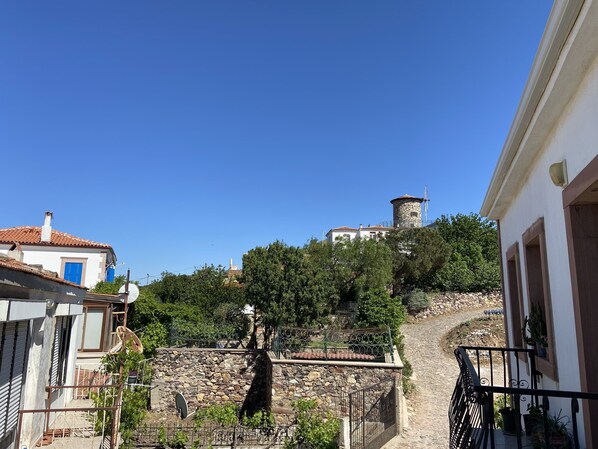 A stone wall with a gate, a clear sky, and buildings with red-tiled roofs. - Mai Otel Cunda (Ayvalik)