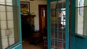 A room with a teal door, a wooden bench, a patterned rug, and a deer head mounted on the wall. - River House on the McKenzie  (Rainbow)