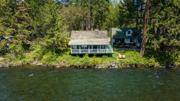 A cabin with a green roof and white trim, surrounded by dense forest and a river. - River House on the McKenzie  (Rainbow)