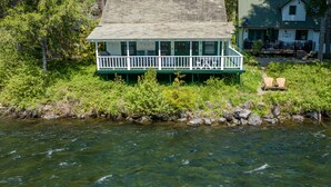 A house with a green porch and a dock extending into a river, surrounded by dense greenery. - River House on the McKenzie  (Rainbow)