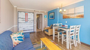 Un salon avec un canapé, une table à manger avec des chaises, un banc et un couloir menant à une autre pièce.