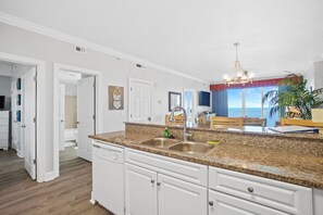 A modern kitchen with granite countertops, white cabinetry, and a double sink.
