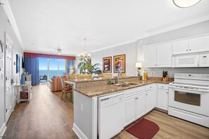 A modern kitchen with white cabinets, a granite countertop, and a built-in dishwasher.