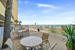 Eine Terrasse mit Sitzgelegenheit, einem Pool und Blick auf den Strand.