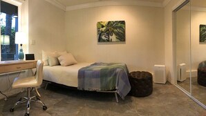 Un dormitorio con cama, escritorio, silla, calentador y ventana.
