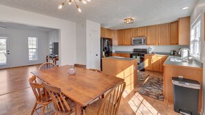 A spacious kitchen with wooden cabinets, a central island, and a dining area with a wooden table and chairs. - Carter Street | Walkable Crozet | Pet-Friendly (Crozet)