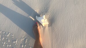 A person's bare feet on a sandy beach with footprints and a piece of seaweed. - Entire Villa for Rent, Leeward / Grace Bay, Short Walk to Sunset Beach (Providenciales)