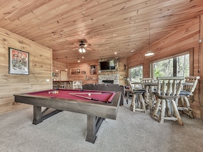 Ein Holzinterieur mit Pooltisch, Sitzgelegenheiten und einem Fernseher.