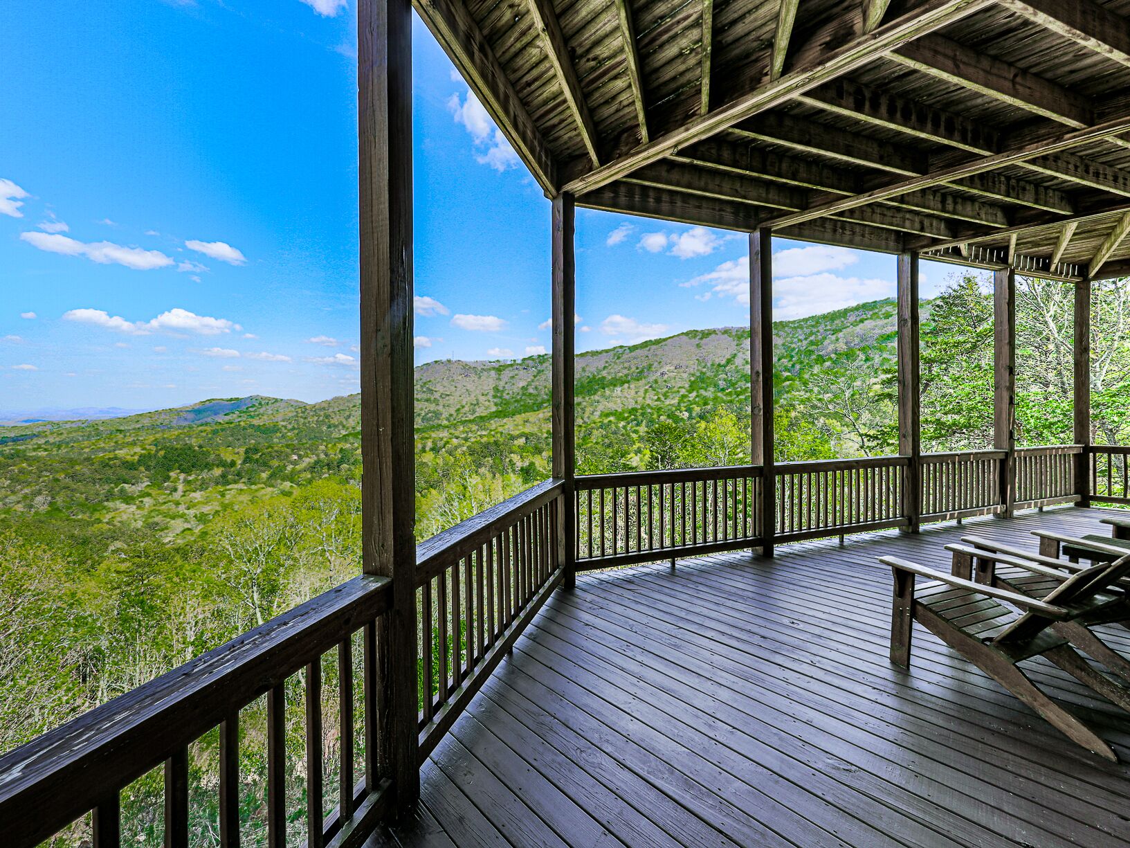 A wooden deck with a view of green hills.