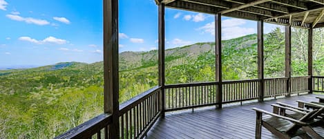 A wooden deck with a view of green hills.