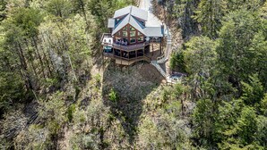 A lodge with a large deck and multiple rooms, surrounded by dense forest. - Blue Ridge Mountaintop Cabin with an amazing View, Hot Tub, Pool Table, Fire Pit (Blue Ridge)