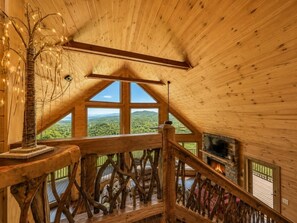 Interior de madera con vista a un paisaje boscoso a través de amplias ventanas.
