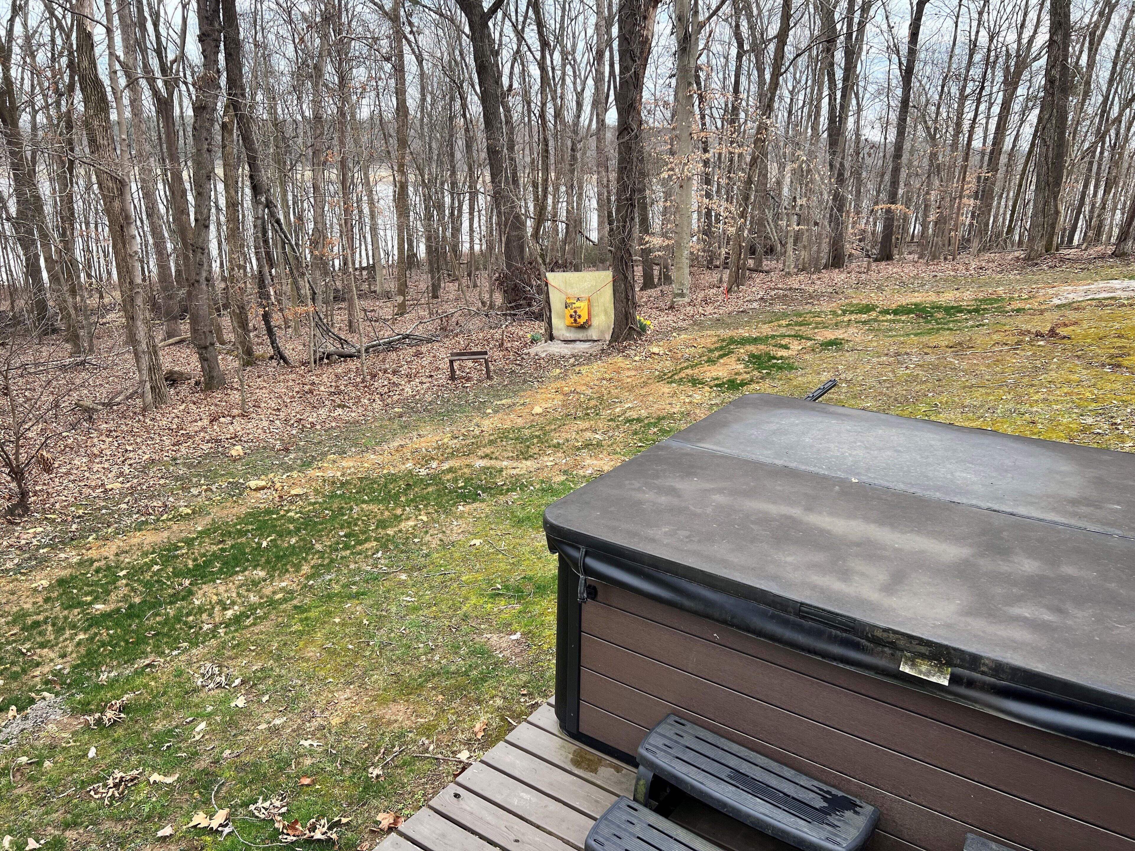 Un bain à remous avec une terrasse en bois et une vue sur une zone boisée.