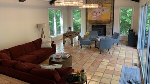 A spacious living room with a red sofa, a fireplace, and a foosball table.