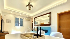 A modern living room with a white sofa, a wooden coffee table, a chandelier, and a large mirror. - Huertas II - 2 bedrooms, in the best area (Madrid)