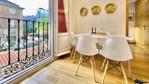 A modern apartment with a balcony, a dining area with white chairs, and decorative plates on the wall. - Huertas II - 2 bedrooms, in the best area (Madrid)
