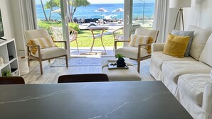 Ein modernes Wohnzimmer mit Meerblick, ausgestattet mit einer Couch, Sesseln und einem Couchtisch.