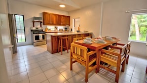 Una cocina con armarios de madera, una estufa y un comedor con sillas y una mesa de madera.