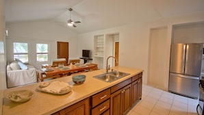 Una cocina moderna con una isla grande, electrodomésticos de acero inoxidable y una zona de comedor con mesa y sillas de madera.