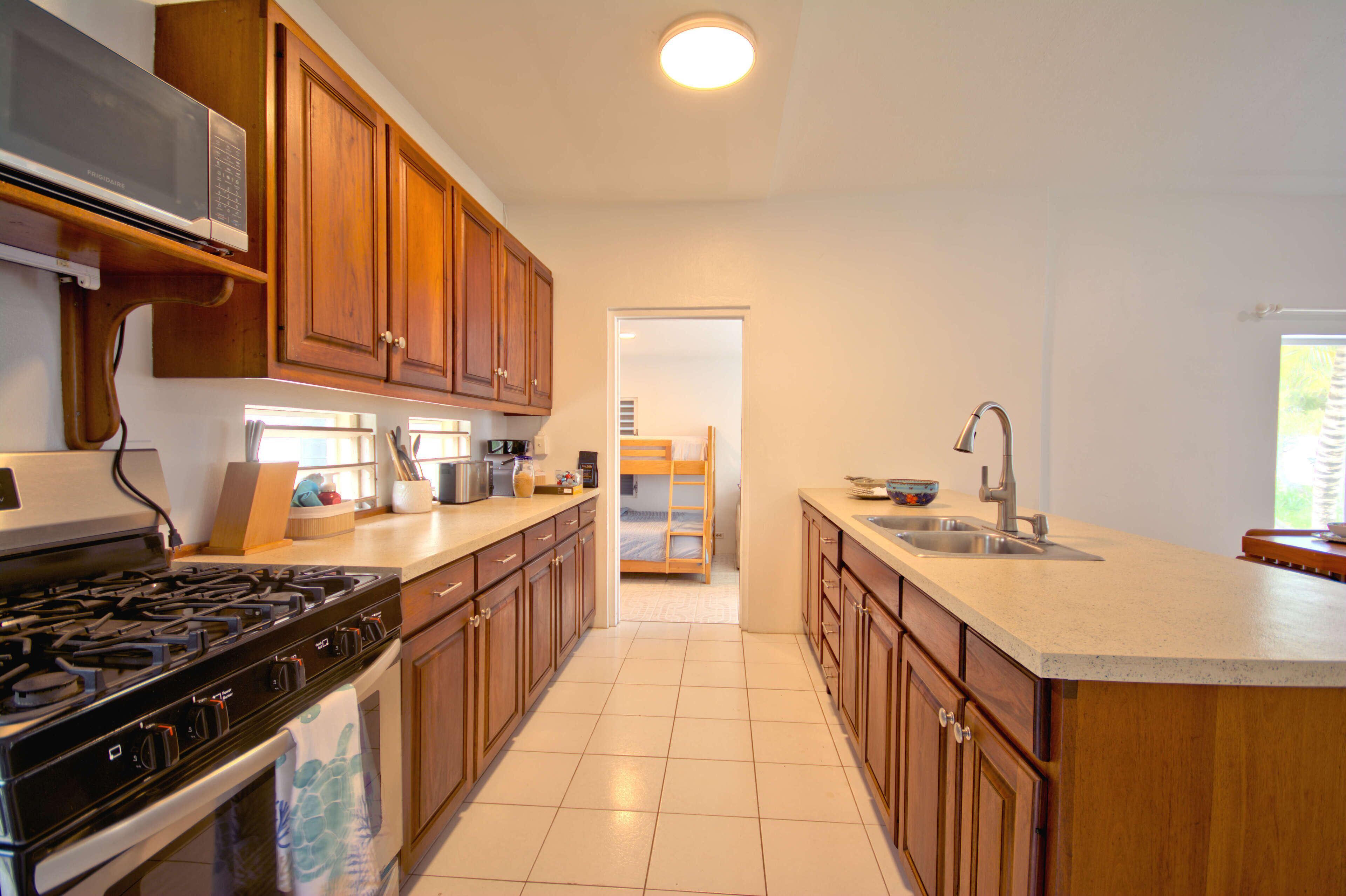 A kitchen with wooden cabinets, a stove, a microwave, and a sink.