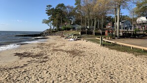 Ein Strand mit einer Holzpromenade, einem kleinen Steg und einer Reihe von Häusern mit einer Flagge.