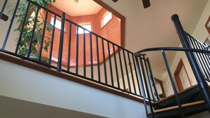 Eine Treppe mit hölzernem Geländer und schwarzen Metallspindeln.