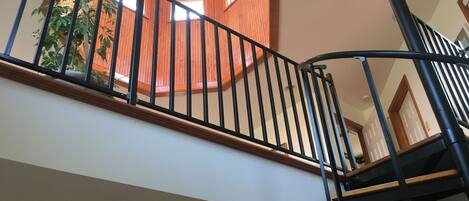 A staircase with a wooden handrail and black metal balusters.