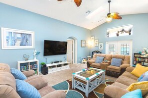 A living room with a flat-screen TV, a sofa, a coffee table, and a bookshelf.