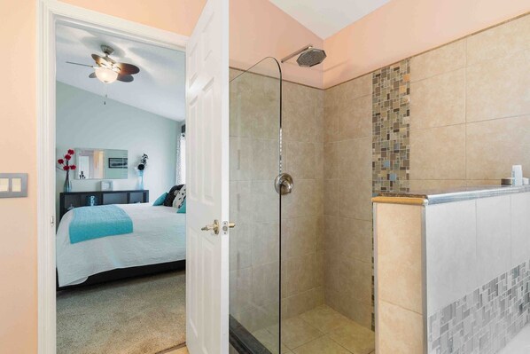 Una habitación de hotel con ducha, cama y baño con pared de azulejos.