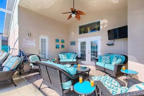 A covered outdoor seating area with wicker furniture and a ceiling fan.
